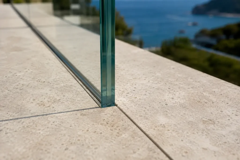Détail de l'encastrement invisible d'un garde-corps en verre feuilleté Saint-Gobain dans un sol en pierres.